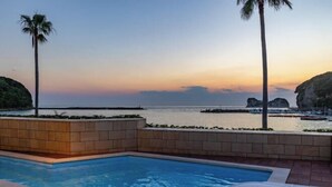 Une piscine avec vue sur la mer et les falaises au coucher du soleil.