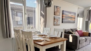 Een eetgedeelte met een houten tafel en stoelen, een bank en kunstwerken aan de muur.