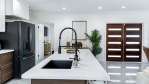 A modern kitchen with a stainless steel refrigerator, a white countertop, and a large sink. - Beautiful Tropical Villa with Private Pool / Pool Bar /Grill / Sandy Beach (Nassau)