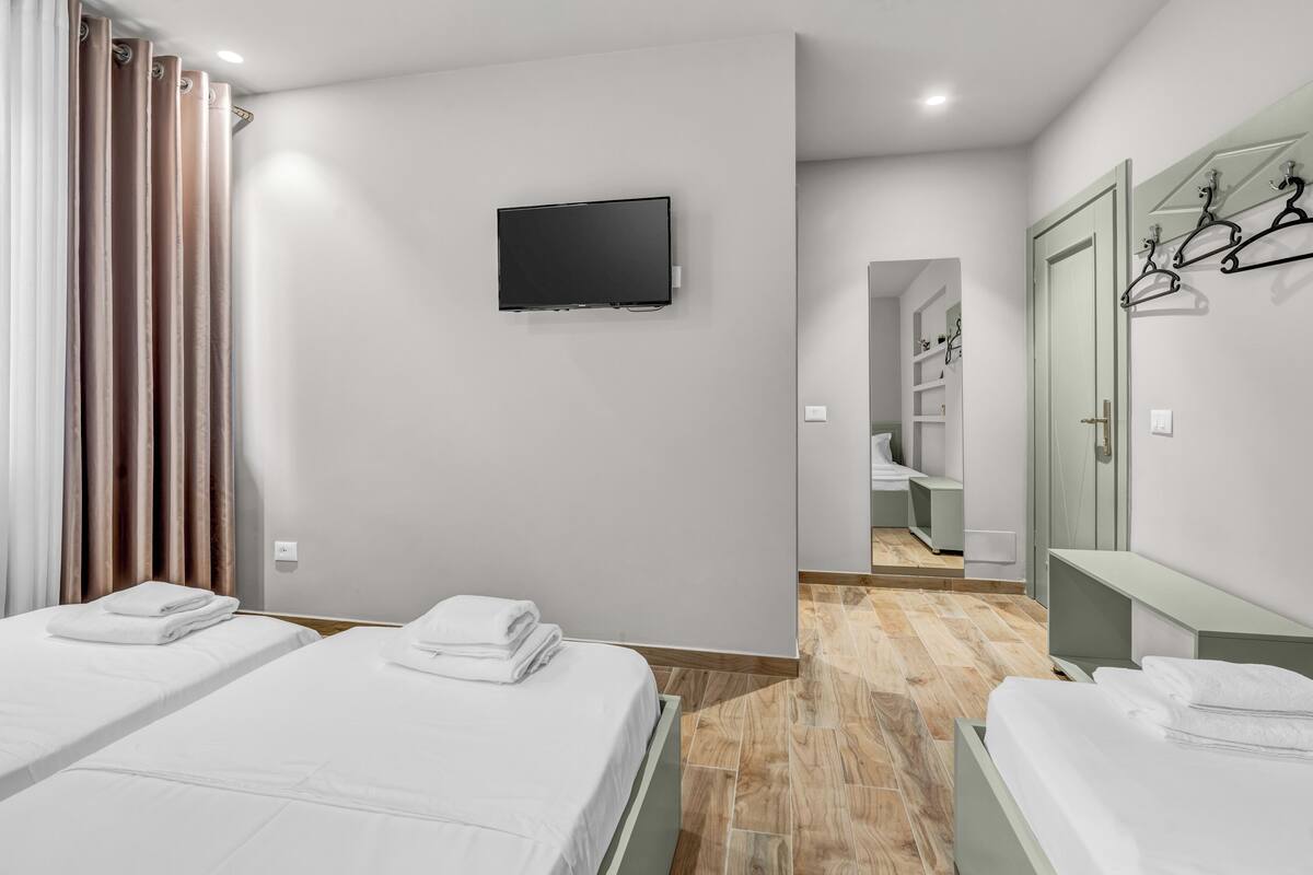 Une chambre d’hôtel avec deux lits, une télévision, un miroir et une armoire.