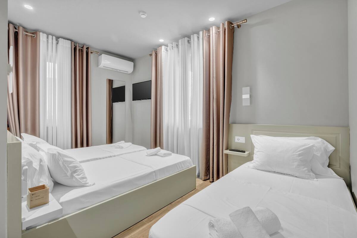 Une chambre d’hôtel avec deux lits, un téléviseur à écran plat et un système de climatisation.