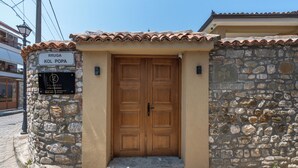 Un bâtiment en pierre avec une porte en bois et une enseigne sur laquelle on peut lire « RRUGA KOL POPA ».