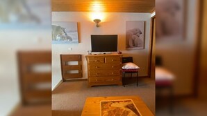 A cozy room with a wooden dresser, a television, and framed pictures on the walls. - Apartment Les Saisies (Hauteluce)