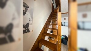 A wooden staircase with a handrail, leading to a landing with a small table and a chair. - Apartment Les Saisies (Hauteluce)