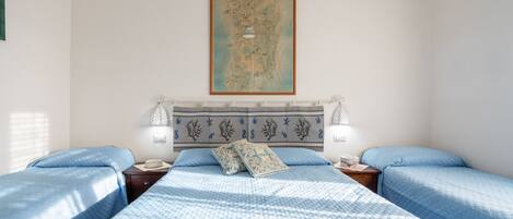 A bedroom with two beds, a map on the wall, and two bedside lamps.