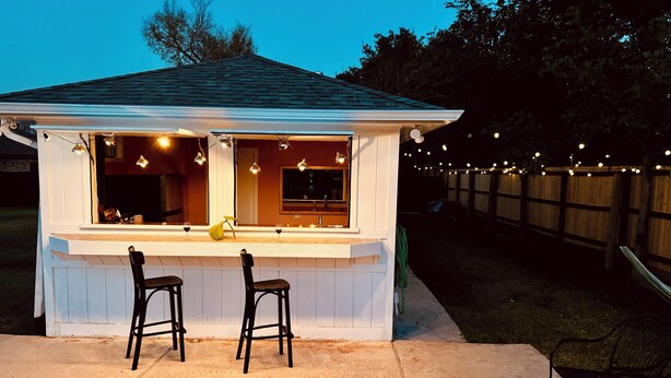 A small outdoor bar with two black bar stools and a white counter. - Vibey & Chill Pool House- Pool, Slide & Hot Tub! Outdoor Bar! Events/Parties! (College Station)