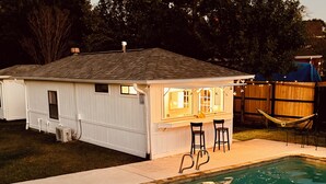 A house with a swimming pool, a small deck, and a hammock. - Vibey & Chill Pool House- Pool, Slide & Hot Tub! Outdoor Bar! Events/Parties! (College Station)