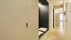 A modern hallway with a light-colored floor, a dark accent wall, and a door with a black handle. - EXQUISITE PARISIAN LUXURY: SOPHISTICATED RETREAT NEXT TO LOUVRE - RUE DE RIVOLI (Paris)