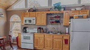 A kitchen with wooden cabinets, a white stove, a microwave, and a refrigerator.