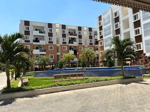 A multi-story hotel with balconies, a swimming pool, and palm trees. - Home Away From Home in Bangalore (Bengaluru)