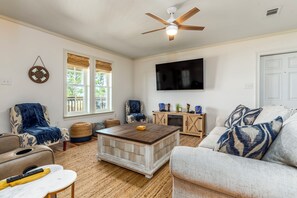 A living room with a ceiling fan, a TV mounted on the wall, a coffee table, and a sofa.