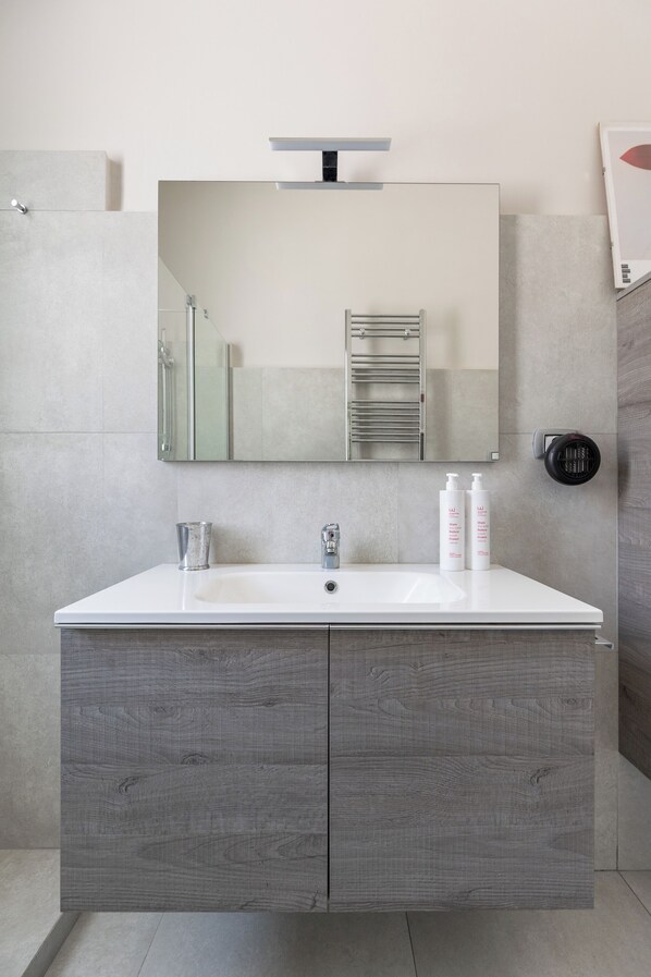 A bathroom with a white sink, a mirror, and a towel rack.