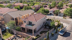 A residential area with houses featuring red-tiled roofs, a paved driveway, and a swimming pool. -  Garden House: A Cozy Retreat (Albuquerque)