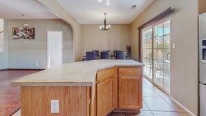 A spacious kitchen with a large island, pendant lighting, and a view through large sliding glass doors. -  Garden House: A Cozy Retreat (Albuquerque)