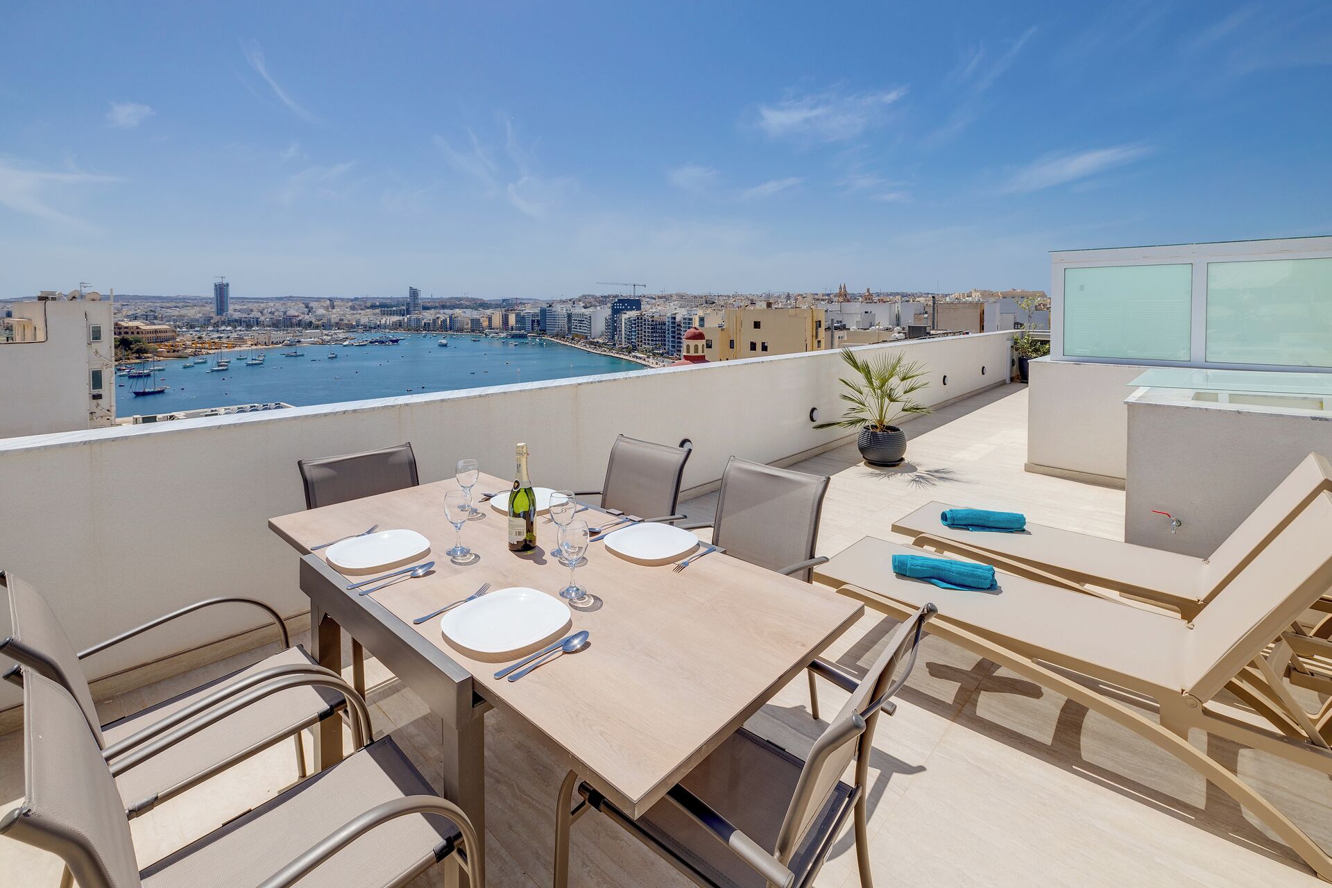 Una terrazza sul tetto con un tavolo da pranzo per due, con vista su una marina e barche.