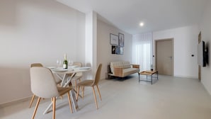 Un salon moderne comprenant un coin repas, un canapé, une table basse et un téléviseur fixé au mur.