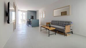 A modern living room with a grey sofa, a coffee table, and a TV mounted on the wall.