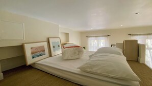 Une chambre d’hôtel avec un grand lit, une table de chevet, une chaise et deux tableaux encadrés au mur.