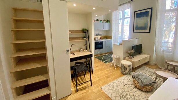 Une cuisine moderne avec un coin repas, un escalier et un salon comprenant un canapé et une table basse.
