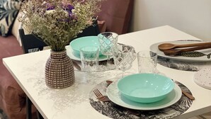 Une table à manger dressée avec des assiettes, des verres et un vase de fleurs.