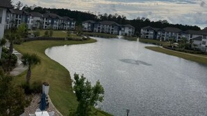 A residential area with a lake, houses, and a patio with outdoor furniture.