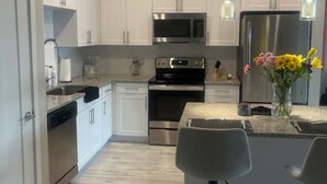 A modern kitchen with white cabinets, stainless steel appliances, and a central island with bar stools.