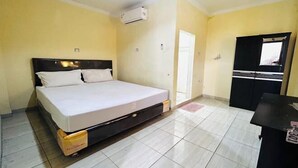 Una habitación con cama, escritorio, armario y aire acondicionado.