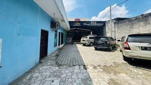 Una calle estrecha con un edificio azul a la izquierda y un cartel que dice 'Homestay 252' a la derecha. Hay coches estacionados a lo largo de la calle.