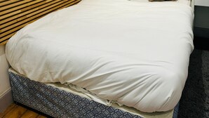 A neatly made bed with a wooden headboard, white bedding, and two patterned pillows. - Cozy Edinburgh Apartment Escape (Edinburgh)