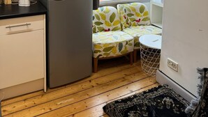 A compact kitchen with a refrigerator, microwave, and kettle, a small dining area with a table and chairs, and a window with curtains. - Cozy Edinburgh Apartment Escape (Edinburgh)