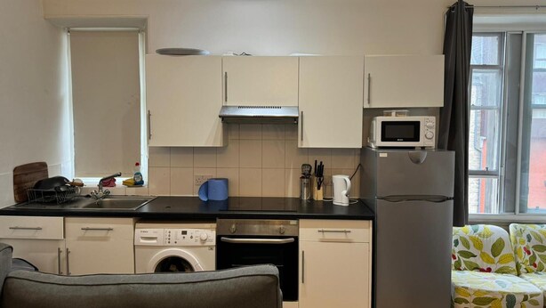 A compact kitchen with a washing machine, dishwasher, microwave, and a small refrigerator. - Cozy Edinburgh Apartment Escape (Edinburgh)