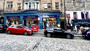 A historic building with shops on the ground floor, including 'Scottish Experience' and 'Cashmere House'. - Cozy Edinburgh Apartment Escape (Edinburgh)