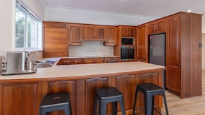 Une cuisine avec des meubles de rangement en bois, un réfrigérateur en acier inoxydable, une machine à café et un évier.