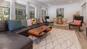 Ein modernes Wohnzimmer mit einem Ecksofa, einem Couchtisch aus Holz und einem Essbereich mit rundem Tisch und Stühlen.