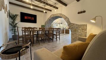 A cozy living room with a stone archway, wooden furniture, and a Netflix sign on the wall.