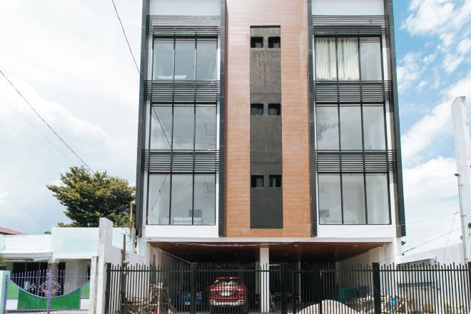 A modern building with a central entrance, large windows, and a metal fence in front.