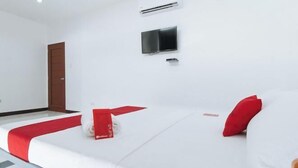A hotel room with a bed, a TV, an air conditioner, and a door. - RedDoorz @ Good 101 Paranaque (Paranaque)