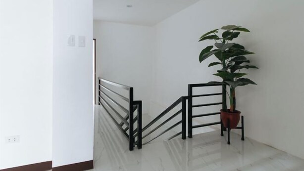 A clean, modern staircase with a metal railing and a potted plant at the top. - RedDoorz @ Good 101 Paranaque (Paranaque)