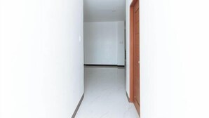 A narrow hallway with white walls and a wooden door on the right. - RedDoorz @ Good 101 Paranaque (Paranaque)