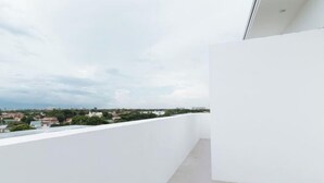 A balcony with a white wall and a view of a cityscape. - RedDoorz @ Good 101 Paranaque (Paranaque)