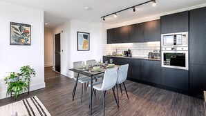 Een moderne keuken met donkere kastjes, een ingebouwde magnetron en een eethoek met een tafel voor vier personen.