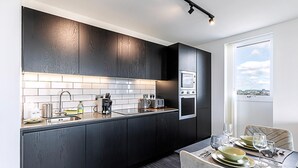 Een moderne keuken met donkere houtkasten, een roestvrijstalen afzuigkap en een eethoek met een tafel gedekt voor twee personen.