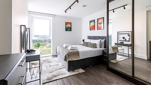 Een moderne slaapkamer met een groot bed, een bureau en een spiegel.