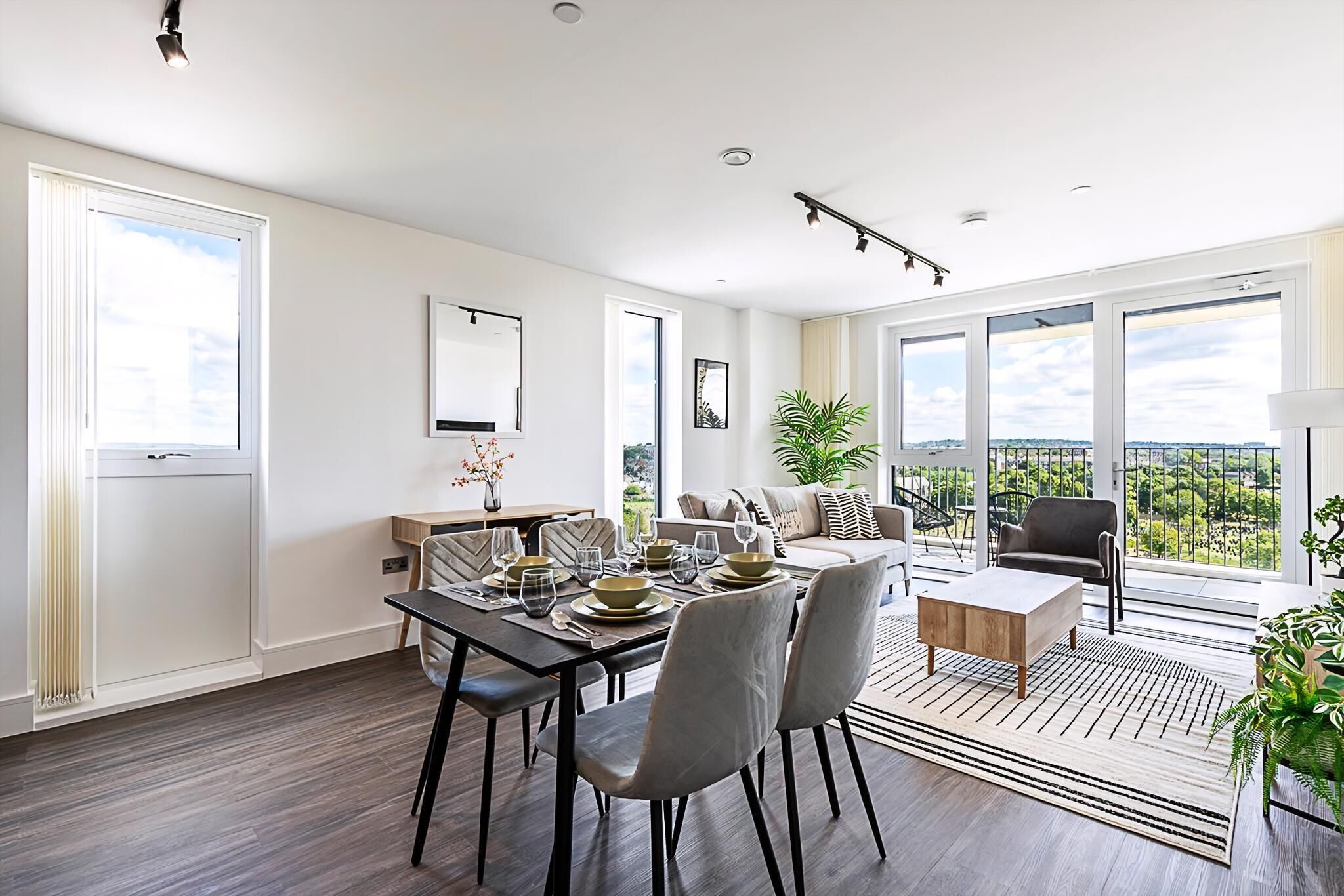 A modern dining area with a table set for four, a sofa, and a view of the outdoors.