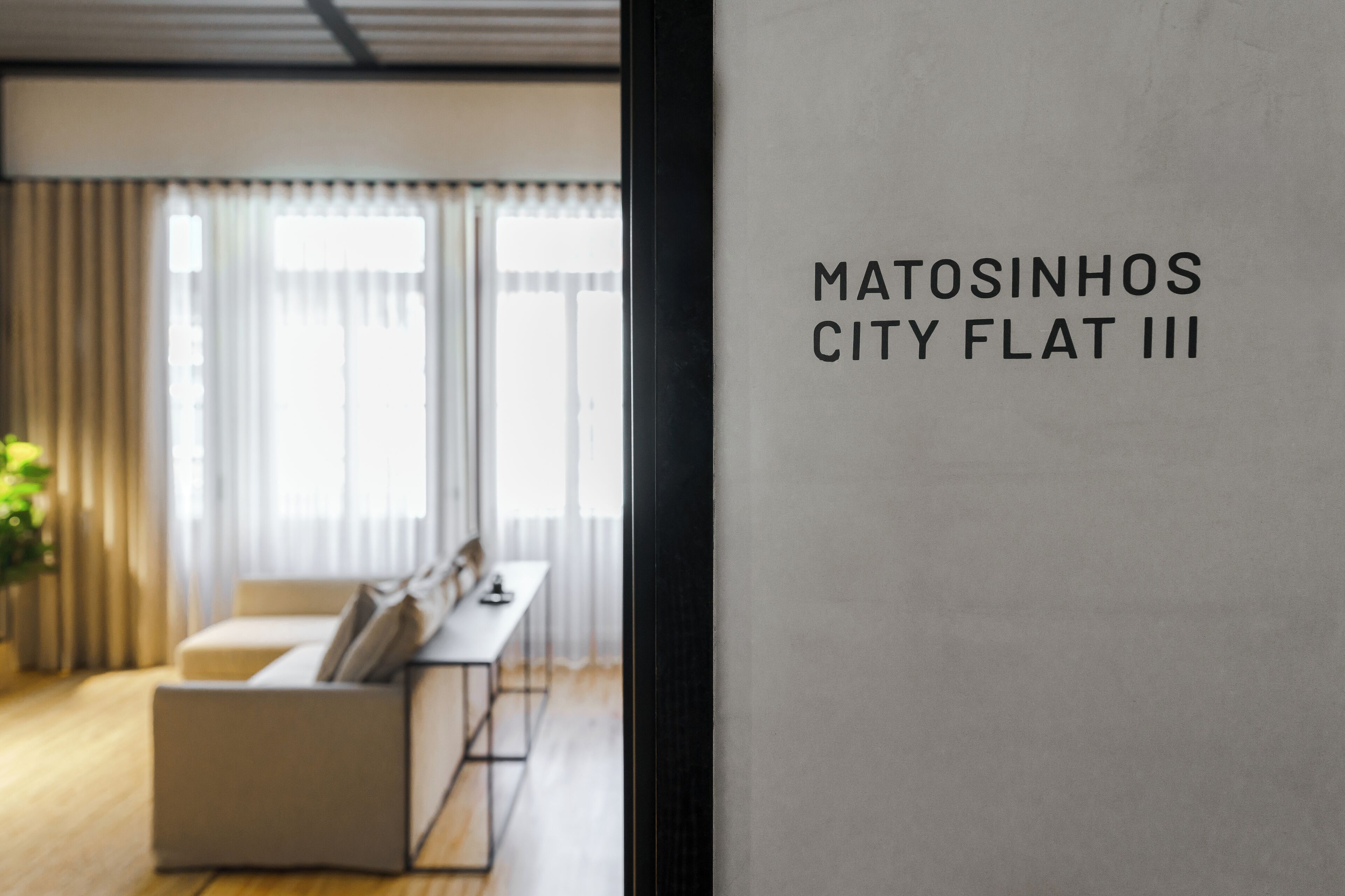 A modern interior with a sofa and a table, and a sign reading "Matosinhos City Flat III".