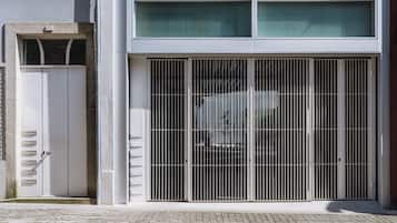 Um edifício com um grande portão de metal, uma porta branca e uma área de entrada pavimentada.