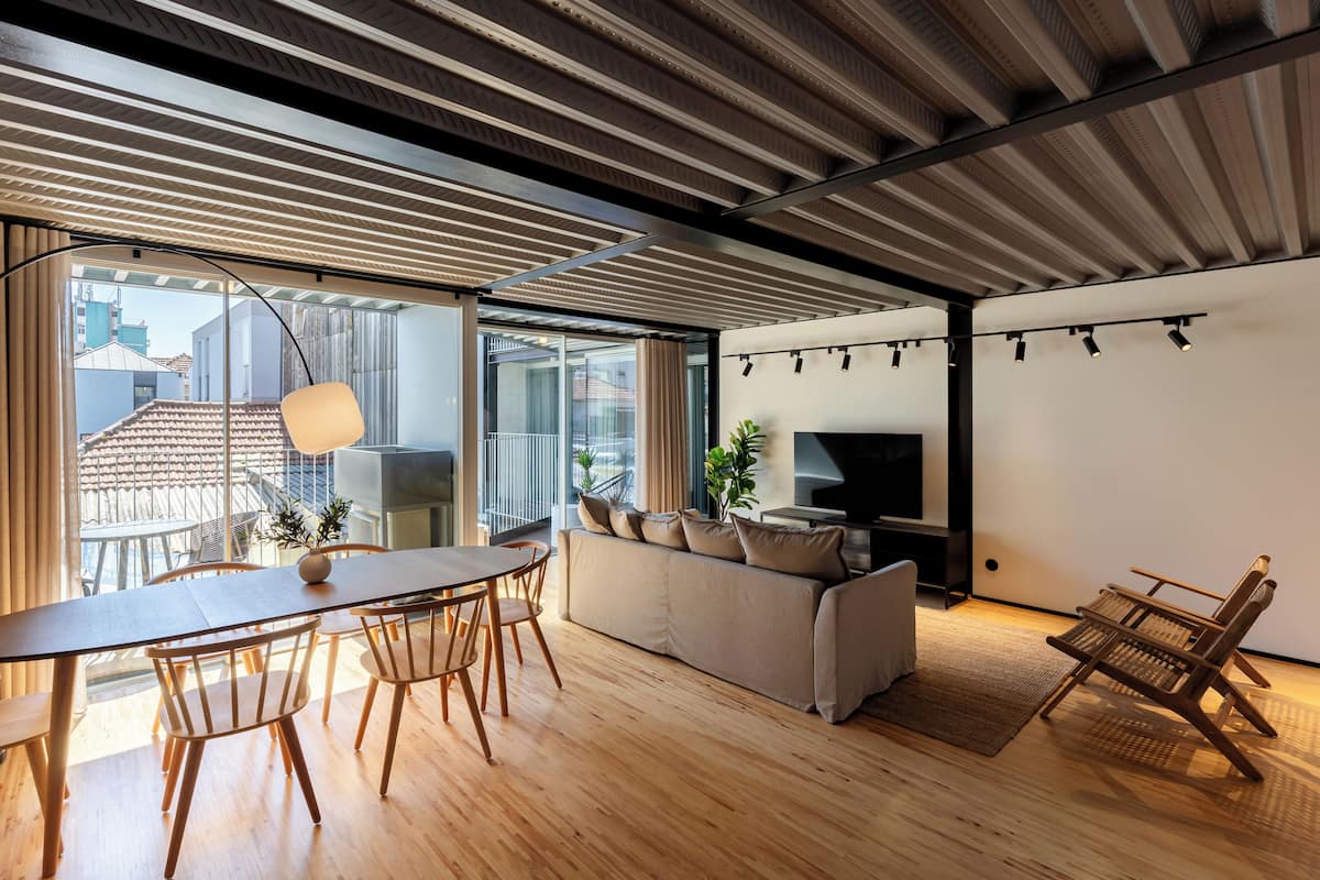 Un salon moderne avec un plancher en bois, un canapé, une table à manger avec des chaises et un téléviseur.