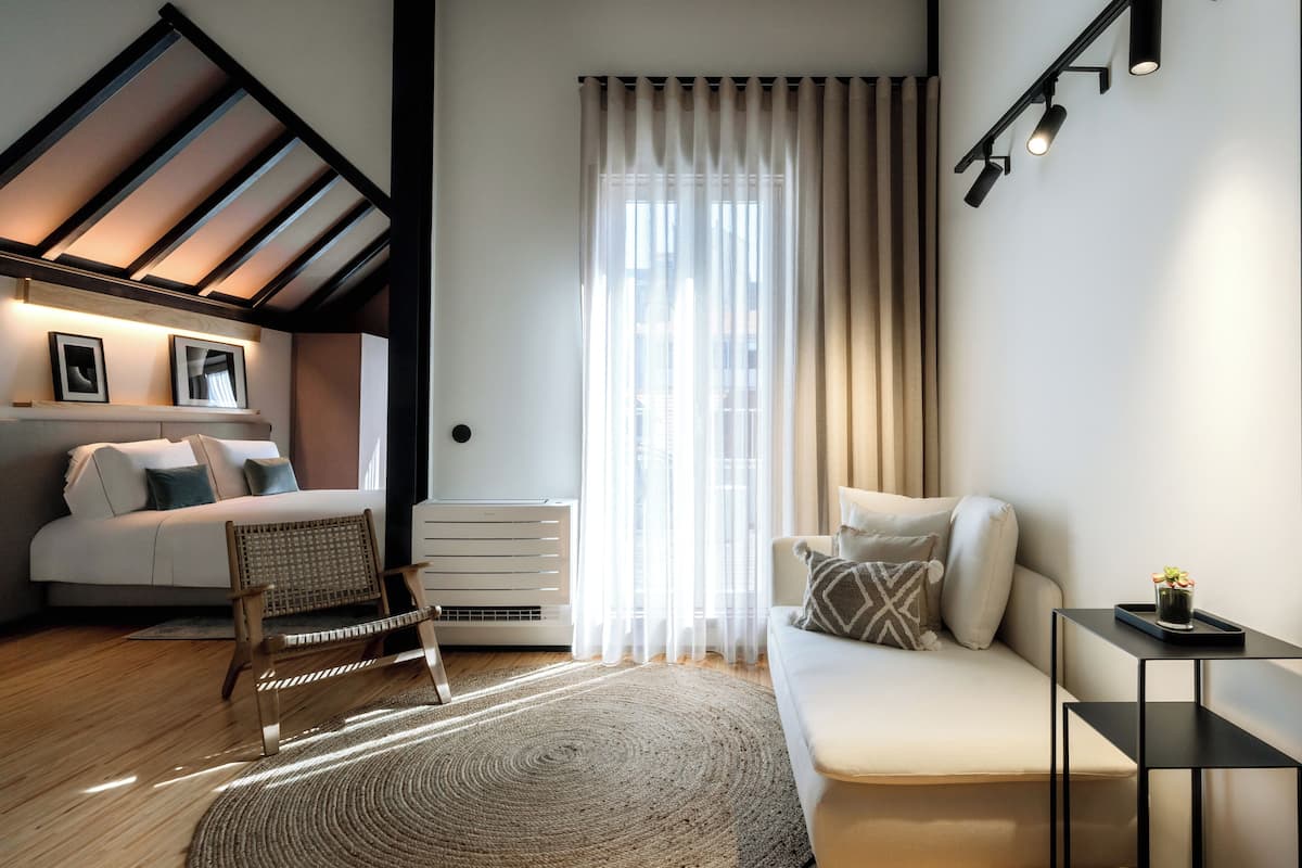 Un salon moderne avec un canapé, un fauteuil, une table basse et une grande fenêtre avec des rideaux.