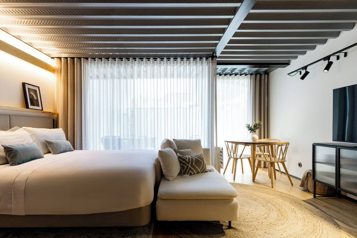 Une chambre d’hôtel moderne dotée d’un grand lit, d’un canapé, d’un coin repas et d’une télévision.