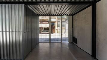 Un interior moderno con pared de metal, suelo de hormigón y vistas al exterior a través de una puerta de cristal.